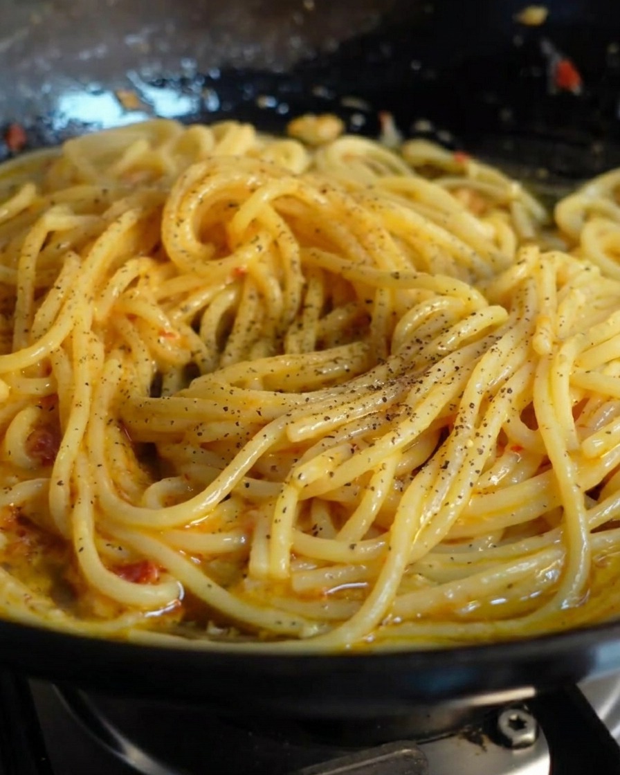 ツヤのあるスパゲッティに挽きたての黒こしょうをふりかけている様子。