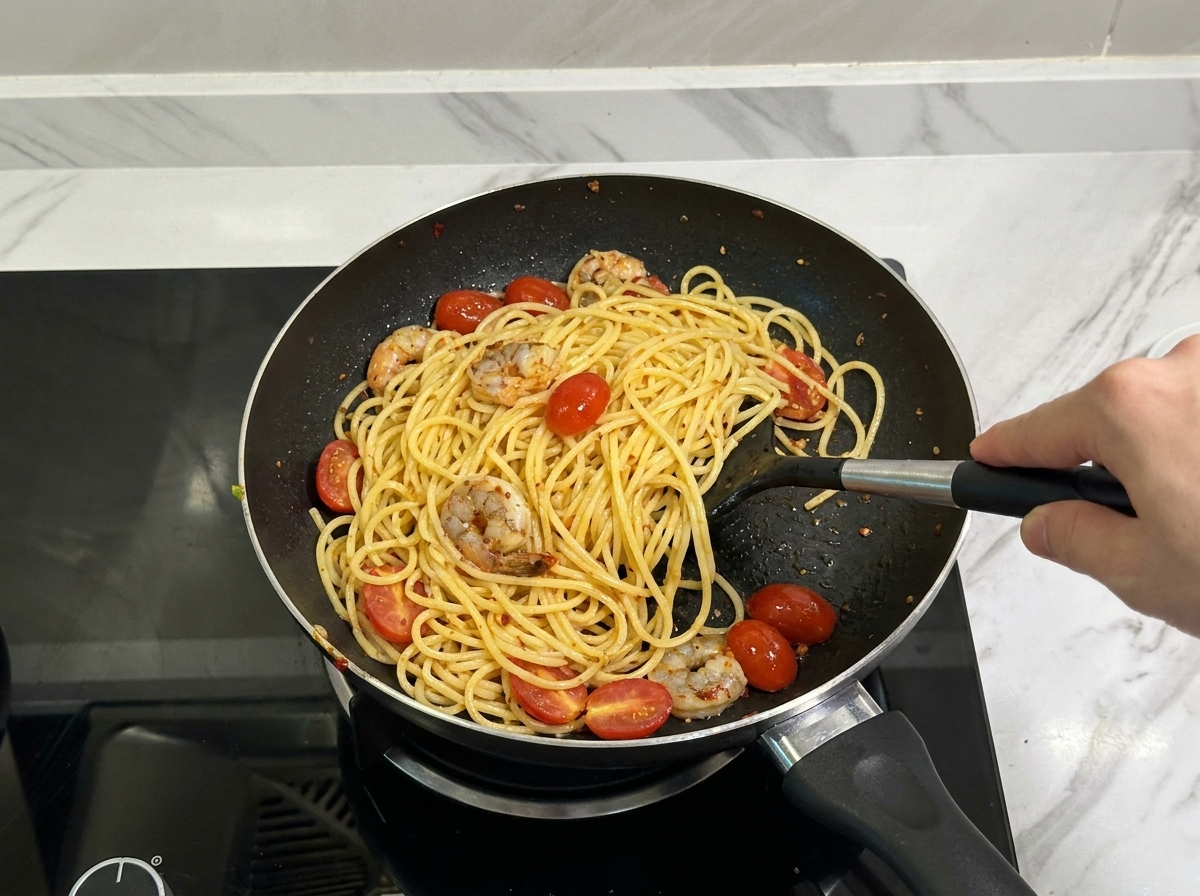 ヘラを使ってパスタと具材を豪快に混ぜ合わせる仕上げ工程。