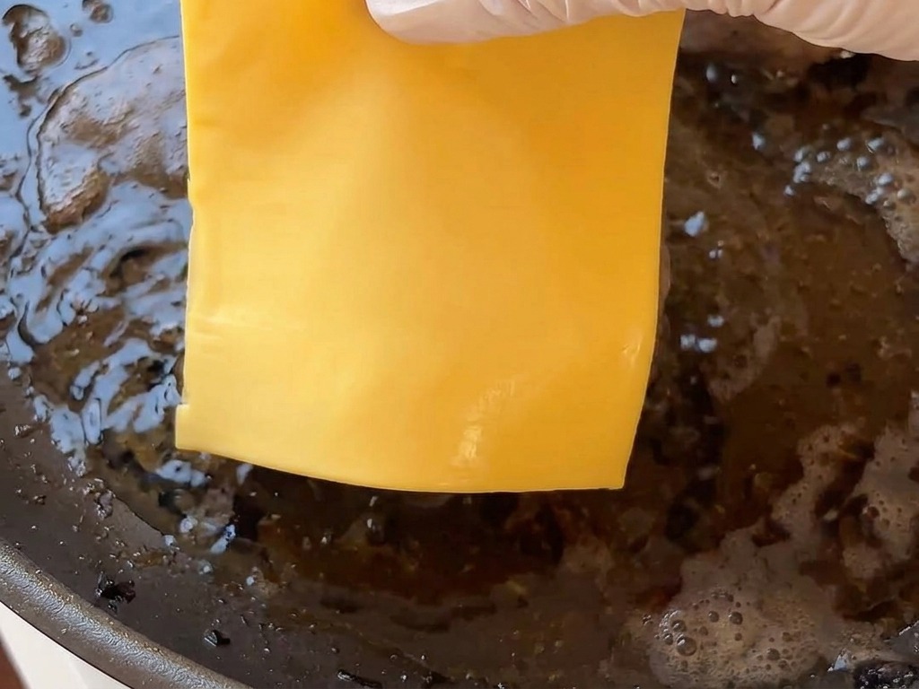 焼けているパティの上に、スライスチーズを丁寧にのせている様子。