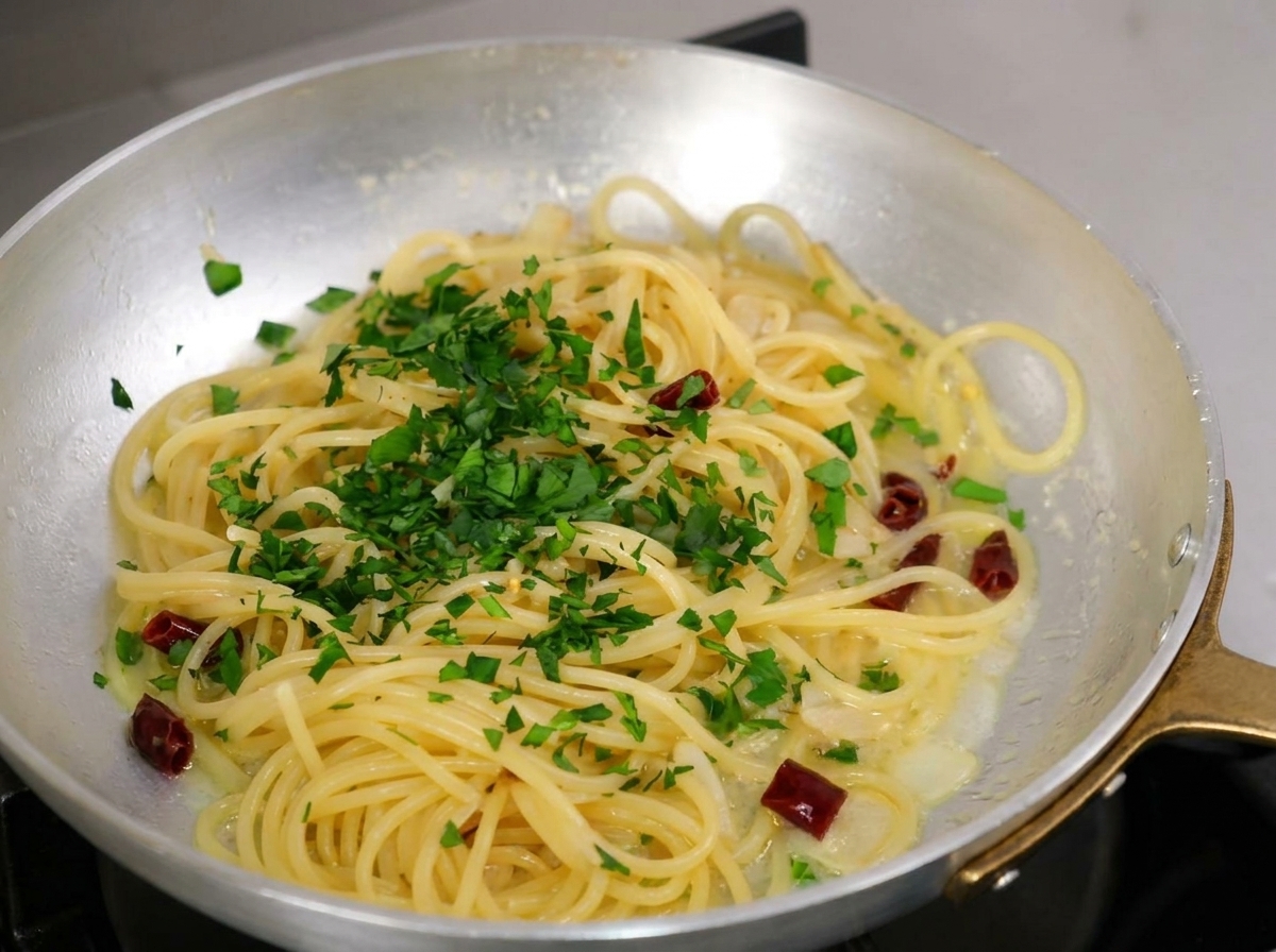 調理済みのスパゲッティに、みじん切りにしたパセリをたっぷりと散らしている様子。