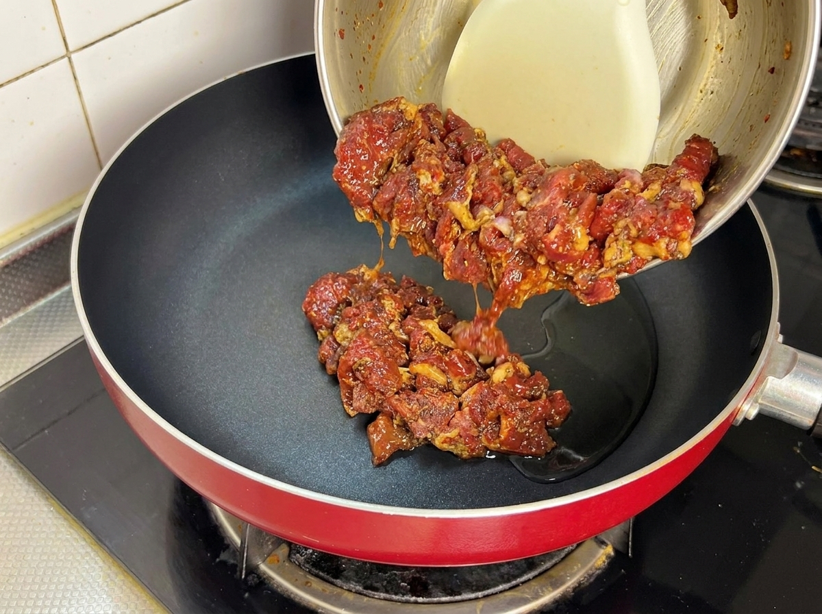 熱したフライパンに下味をつけた牛肉を入れている様子。