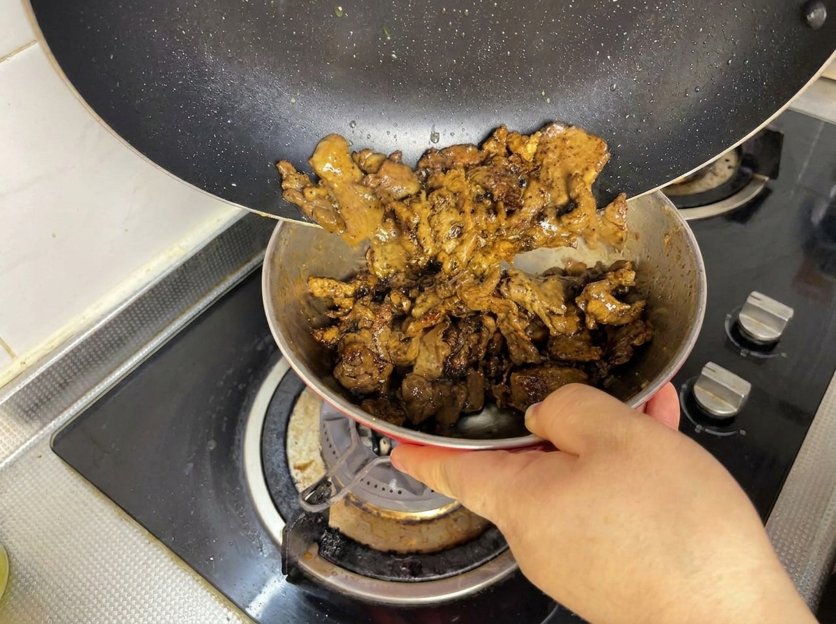 炒めた牛肉をフライパンからボウルへ移している様子。