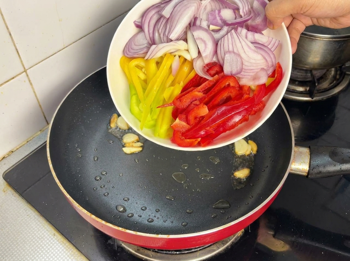 フライパンで玉ねぎとパプリカを炒めている様子。