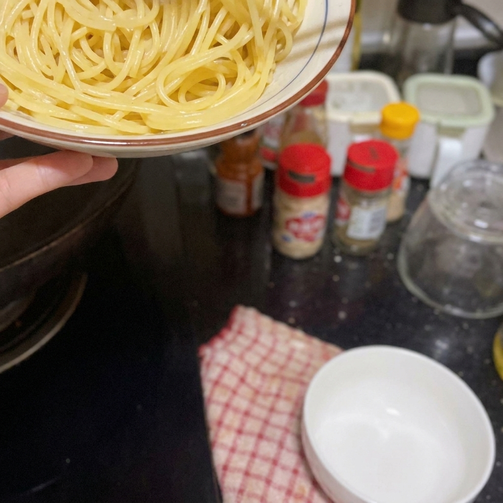 海老やニンニクが入ったフライパンに、茹でたスパゲッティを加えようとしている様子。