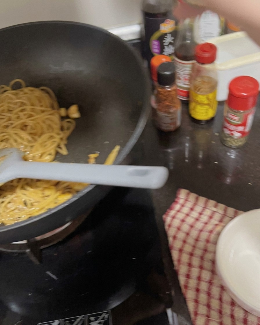 出来上がったパスタにガーリックパウダーやパセリを振りかけている様子。
