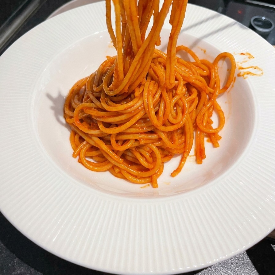 トングを使ってパスタをくるくると巻きながら皿に盛る様子