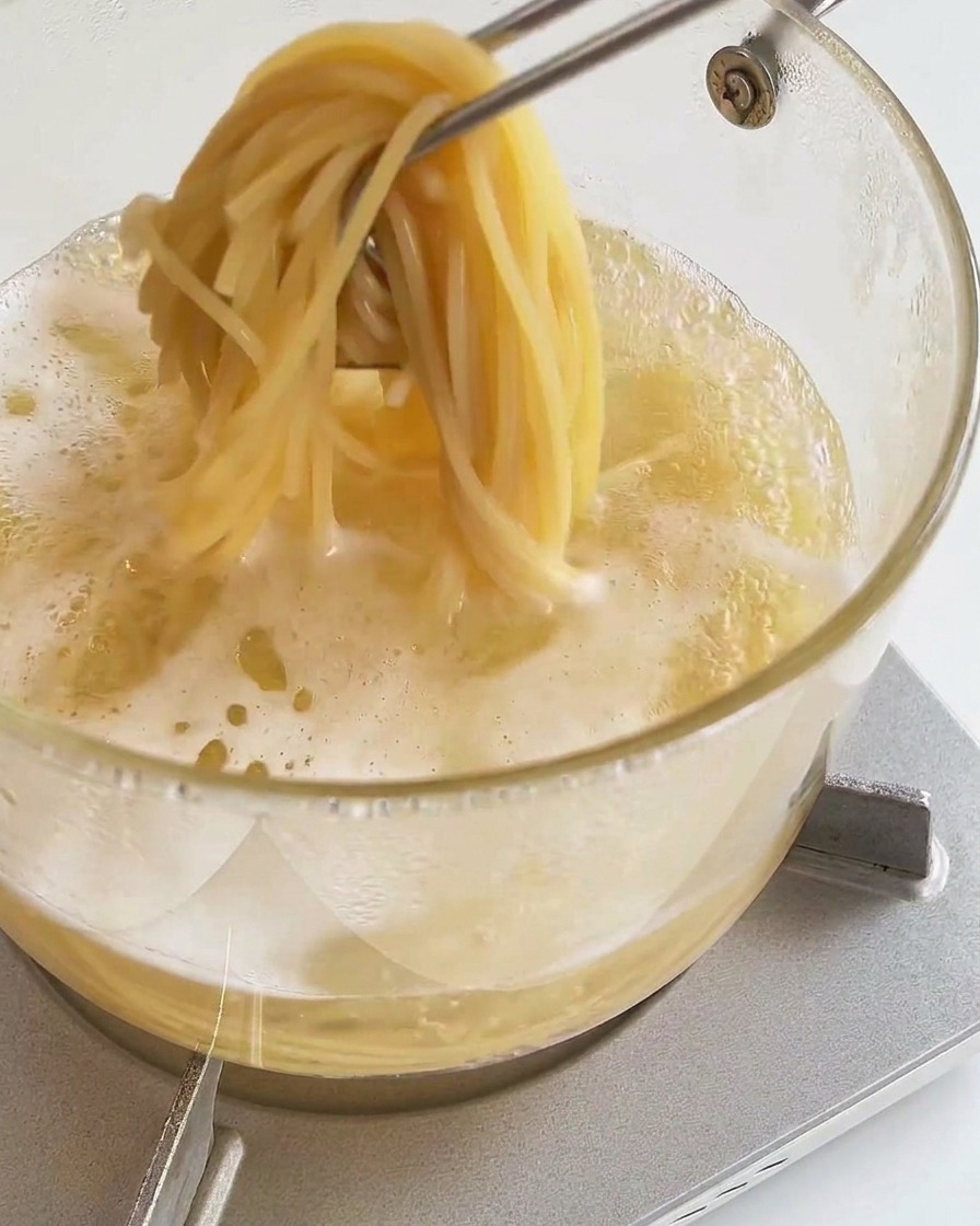トングで茹でたてのスパゲッティを持ち上げている様子