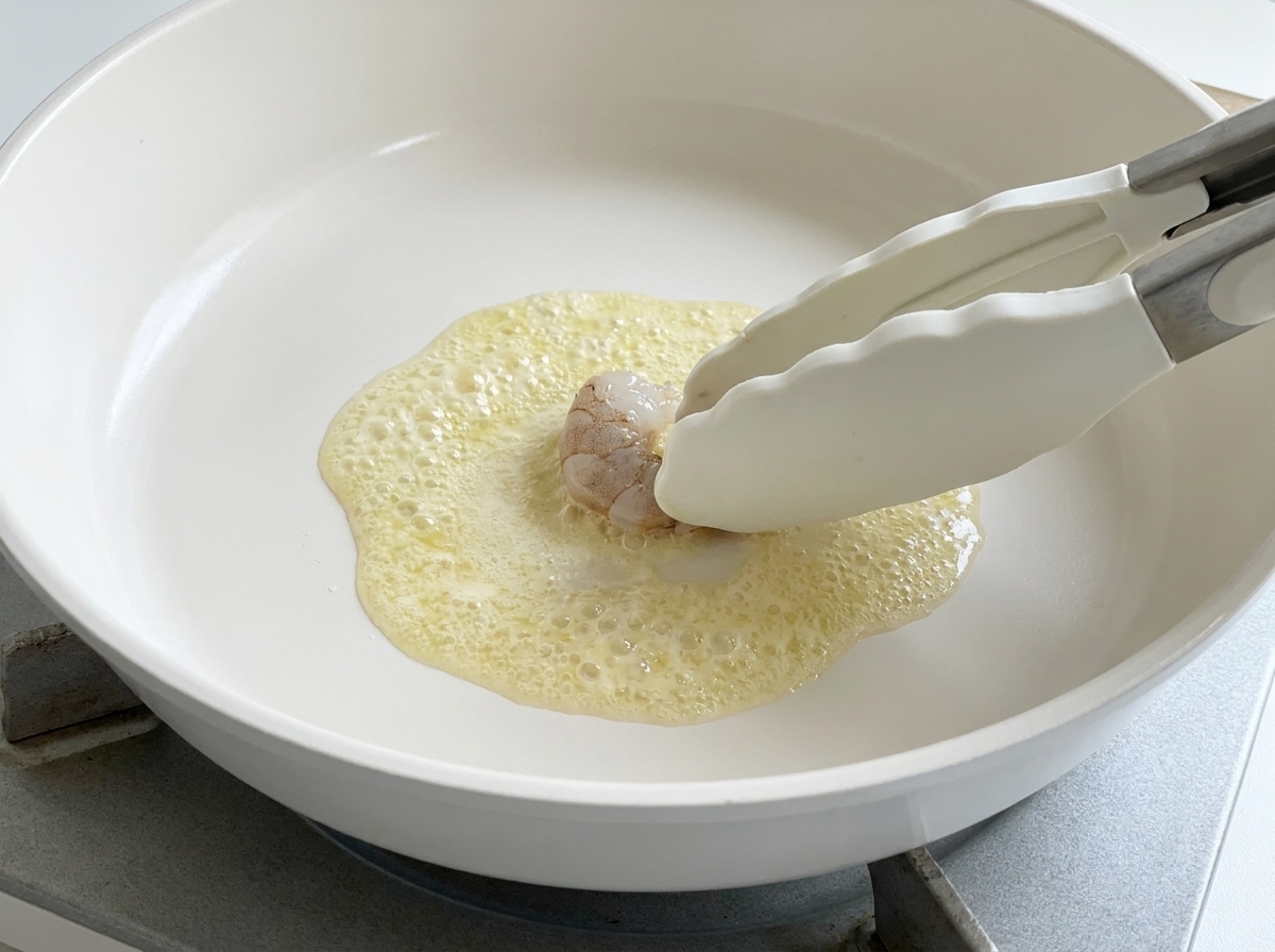 熱したバターの中に生の海老を並べている様子