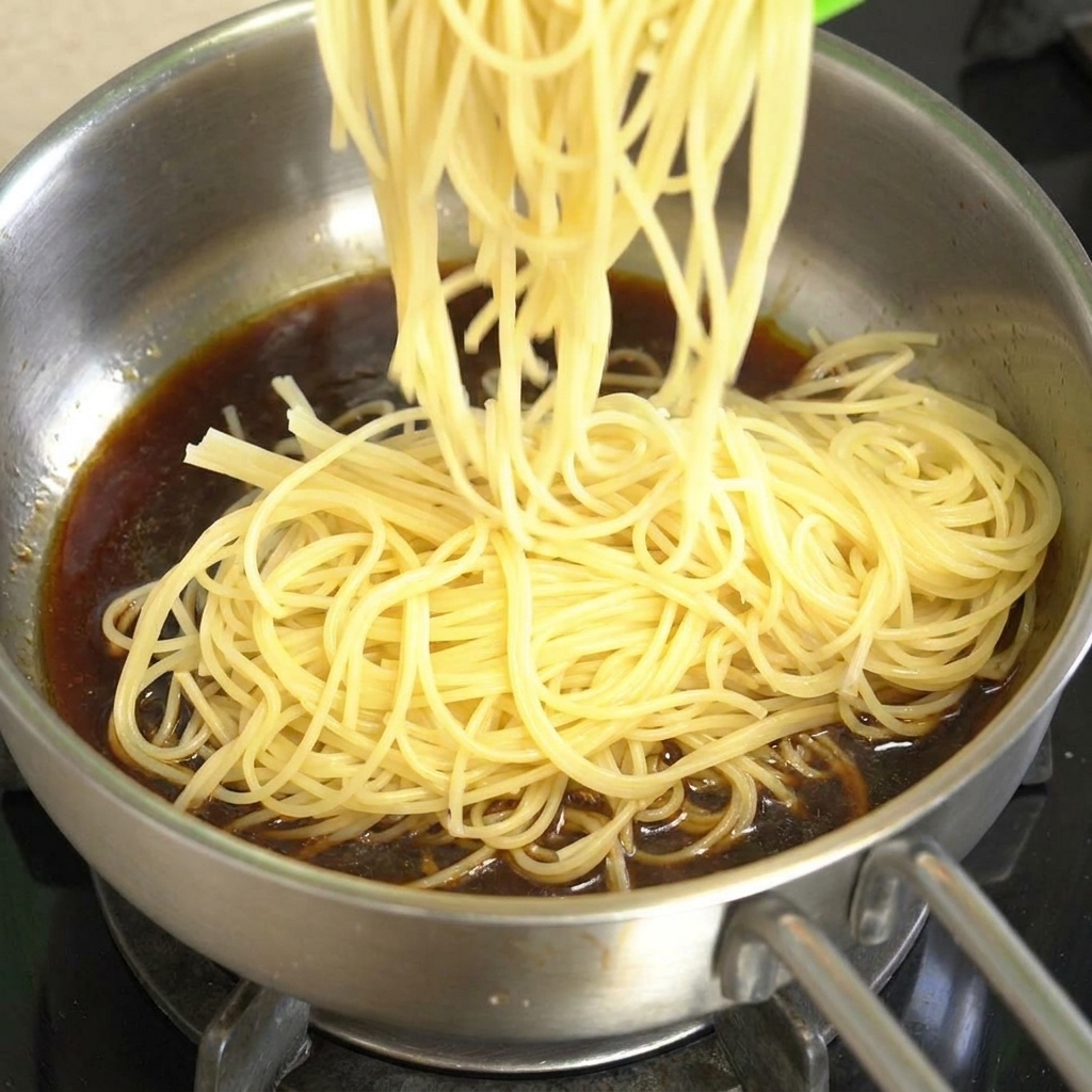 茹で上がったスパゲッティを、牛肉ソースが入ったフライパンに加えている様子。