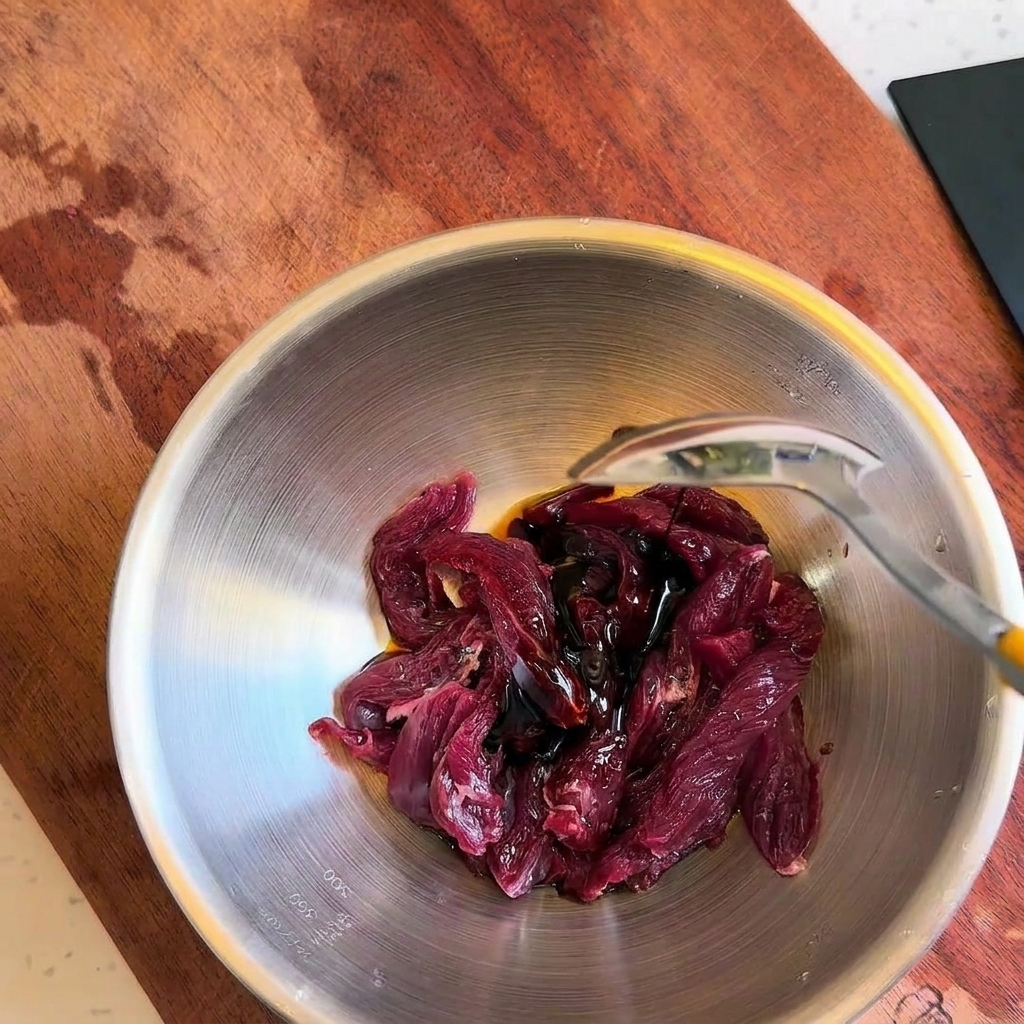 牛肉に調味料を加えて混ぜ合わせる様子。