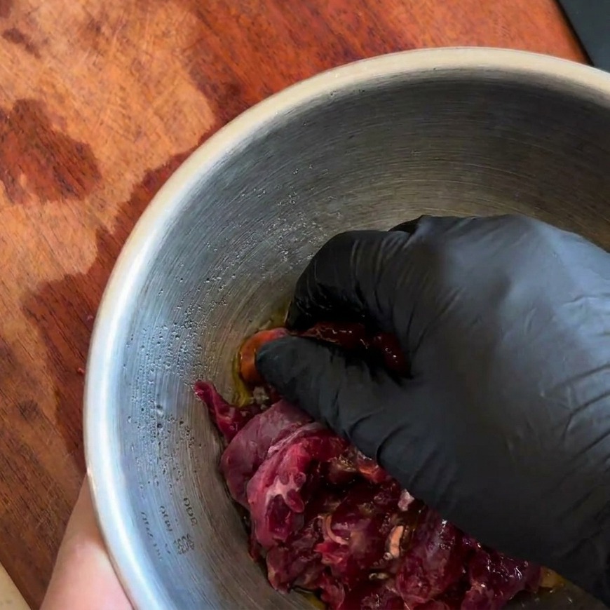 手で牛肉に調味料を揉み込んでいる様子。