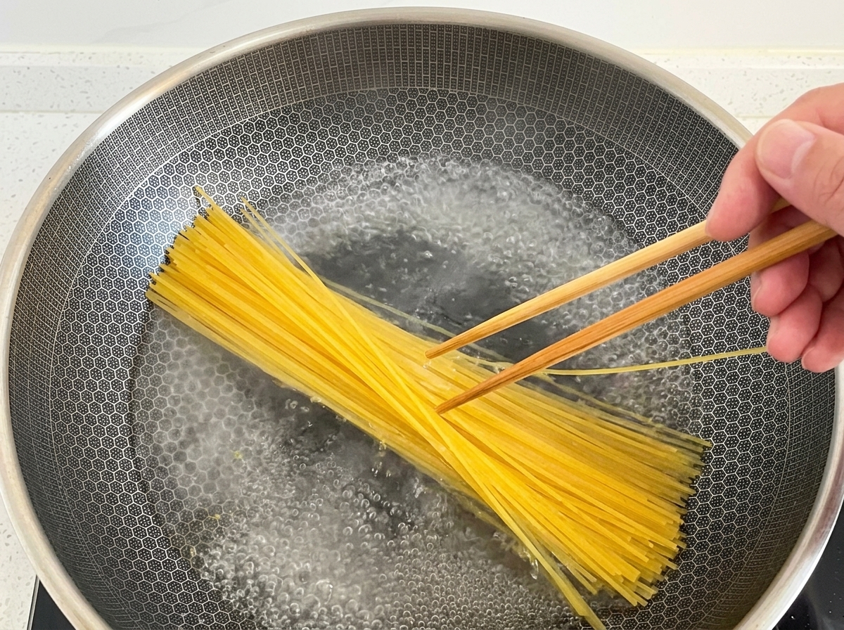 沸騰したお湯にスパゲッティを入れる様子。