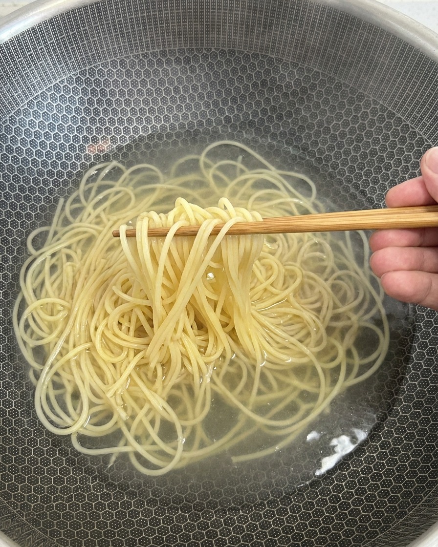 茹で上がったスパゲッティを皿に移す様子。