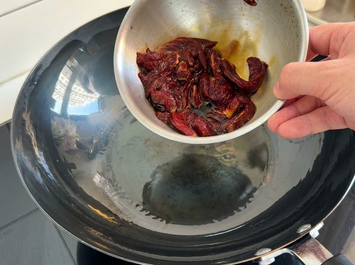 熱した中華鍋に牛肉を入れる様子。