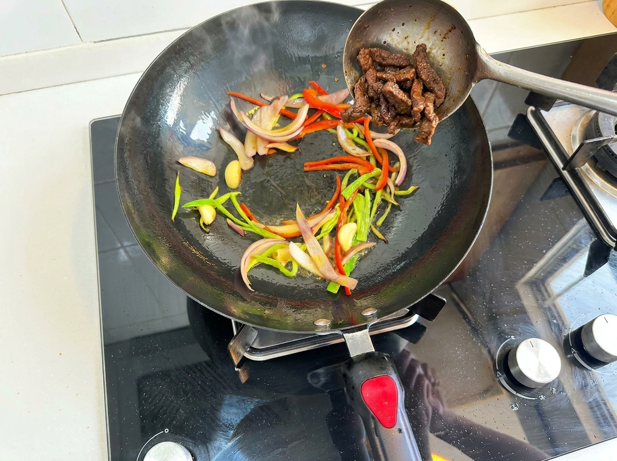 野菜を炒めている鍋に牛肉を戻す様子。