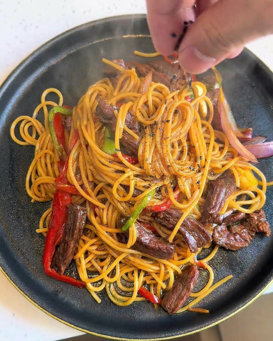 盛り付けたパスタに黒ごまを振る様子。