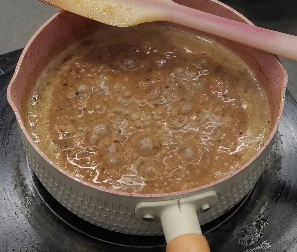とろみが出て光沢のある濃い茶色になった黒胡椒ソースが鍋の中でふつふつとしている様子。
