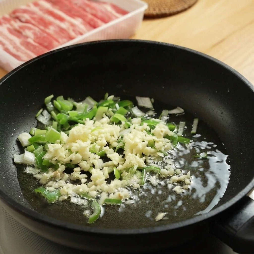 フライパンでみじん切りのにんにくと長ねぎを炒めている様子。