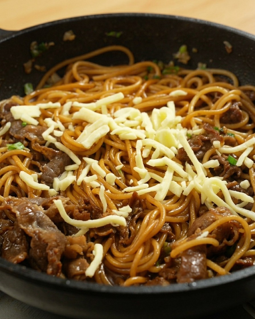 チーズを乗せたスパゲッティに蓋をしたフライパン。