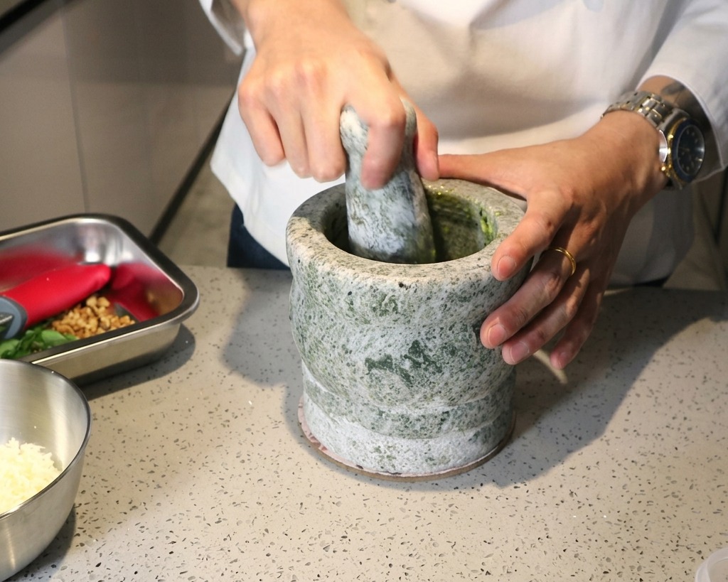 すりこぎを使い、材料を緑色のペースト状にすり潰している様子。
