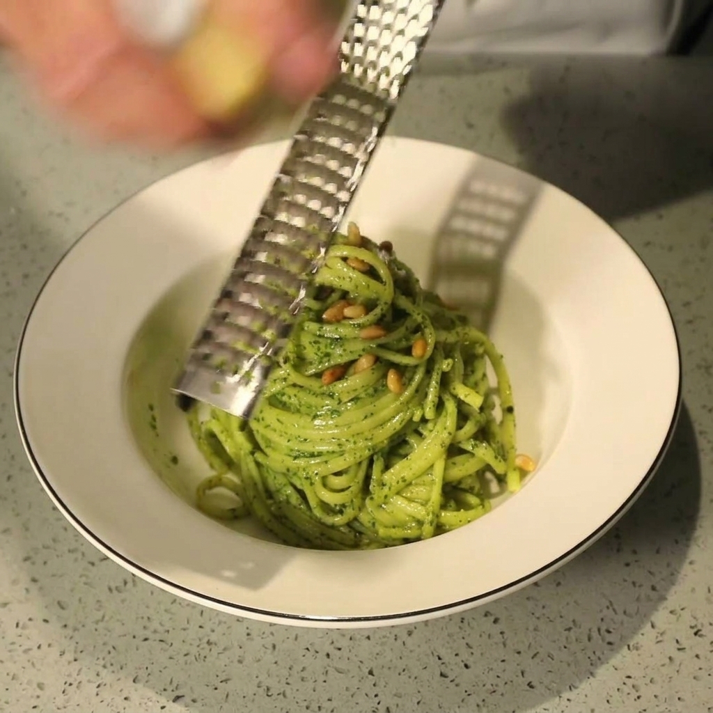 パスタの上から、パルメザンチーズをさらに削りかけている様子。