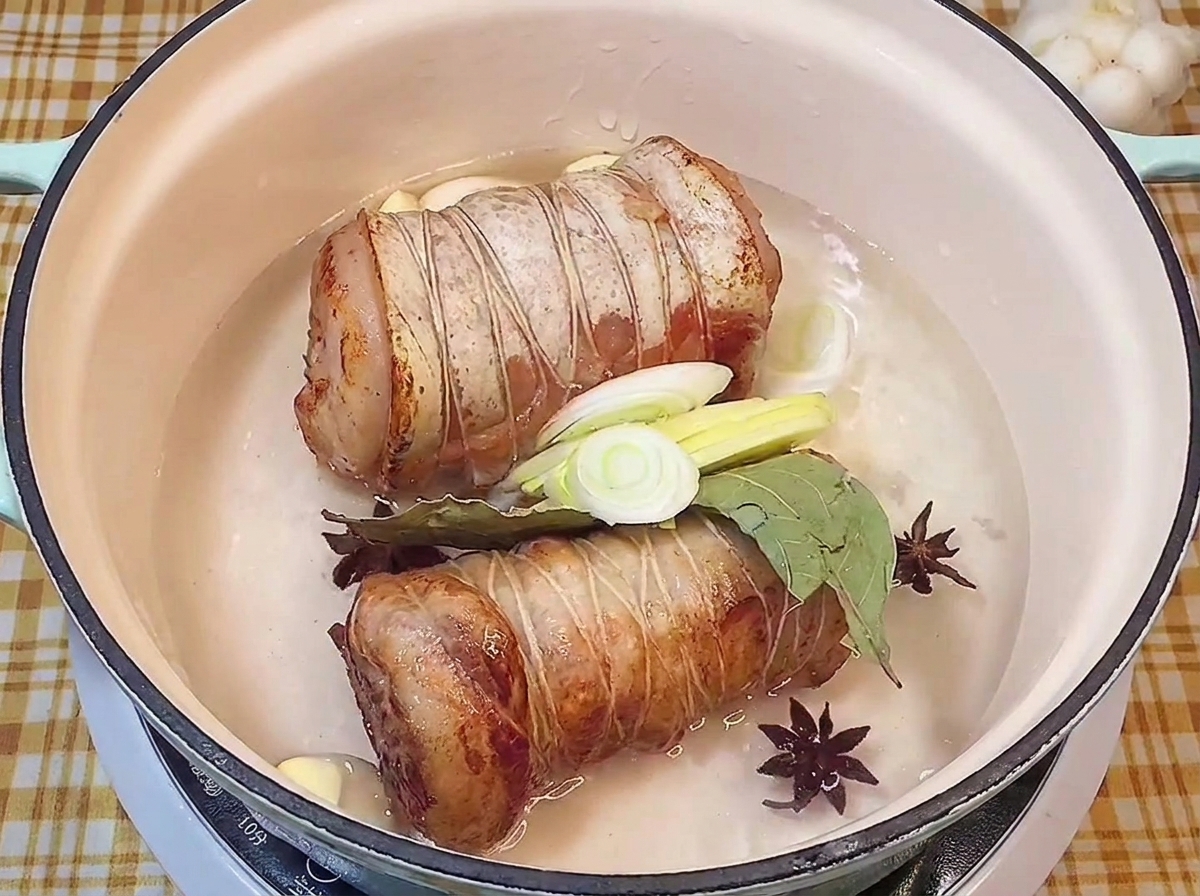 八角、ローリエ、ニンニク、長ねぎと一緒に液体に浸かった焼き色のついた豚肉。