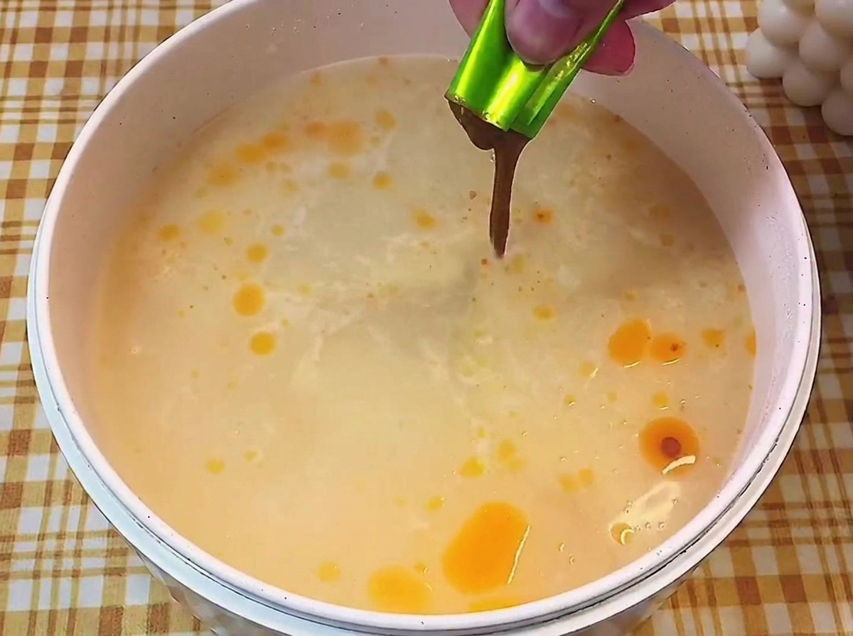 沸騰したお湯に、小袋から濃縮された液体スープを絞り入れている様子。