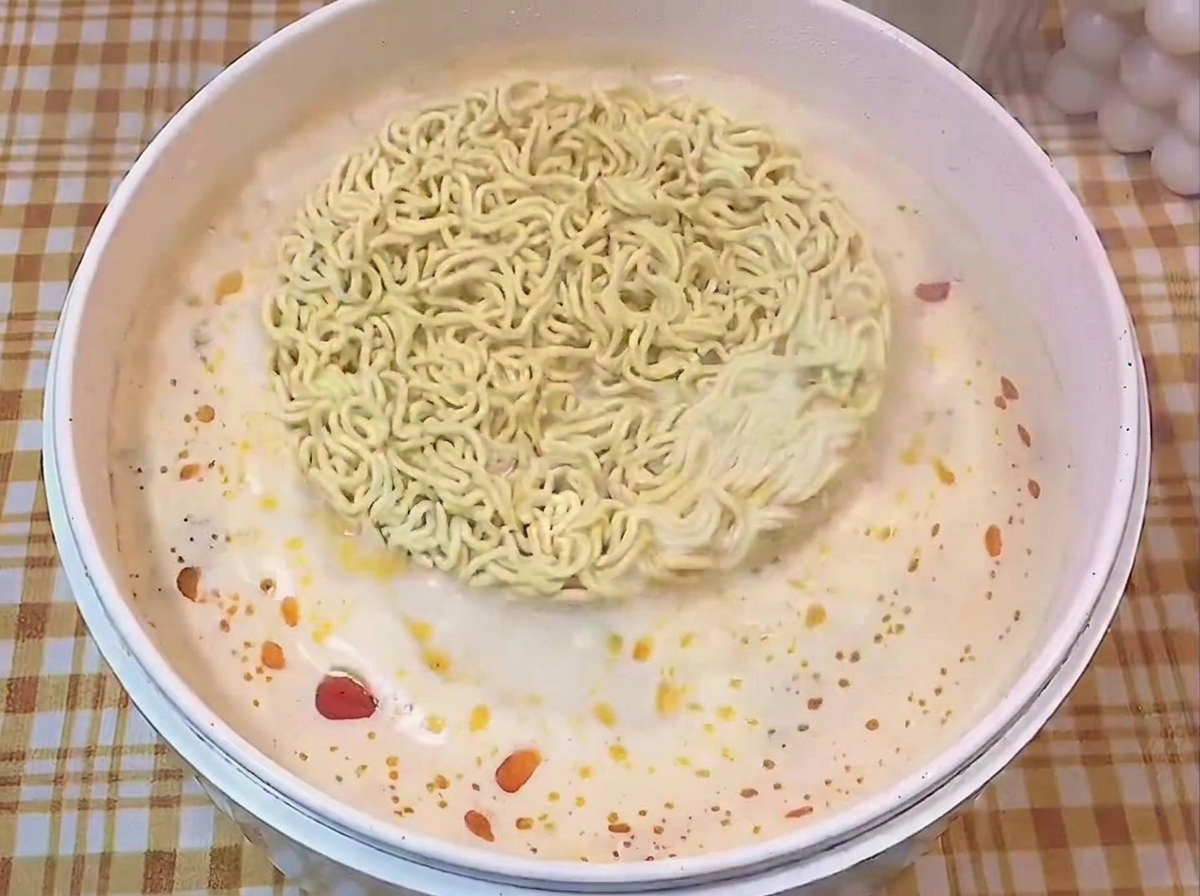 味付けされた沸騰したスープの中で、丸い乾麺の塊が茹でられている様子。