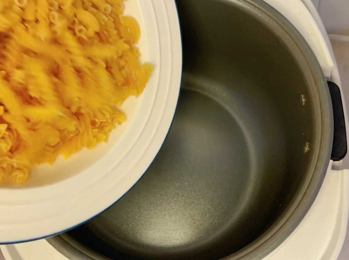 白い皿から炊飯器の釜に乾燥フジッリを入れている様子。