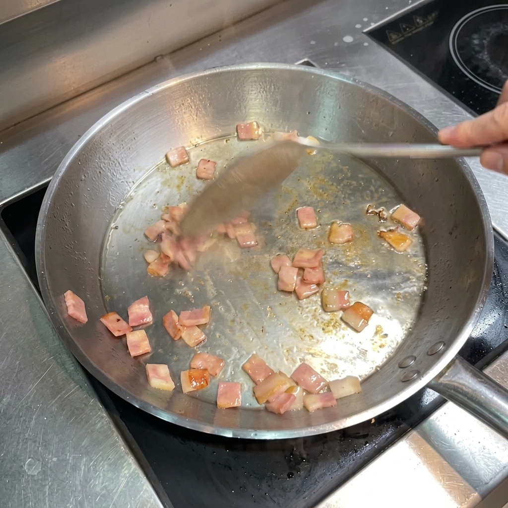 ヘラで混ぜながら、こんがりと色づいたベーコンを炒める様子。