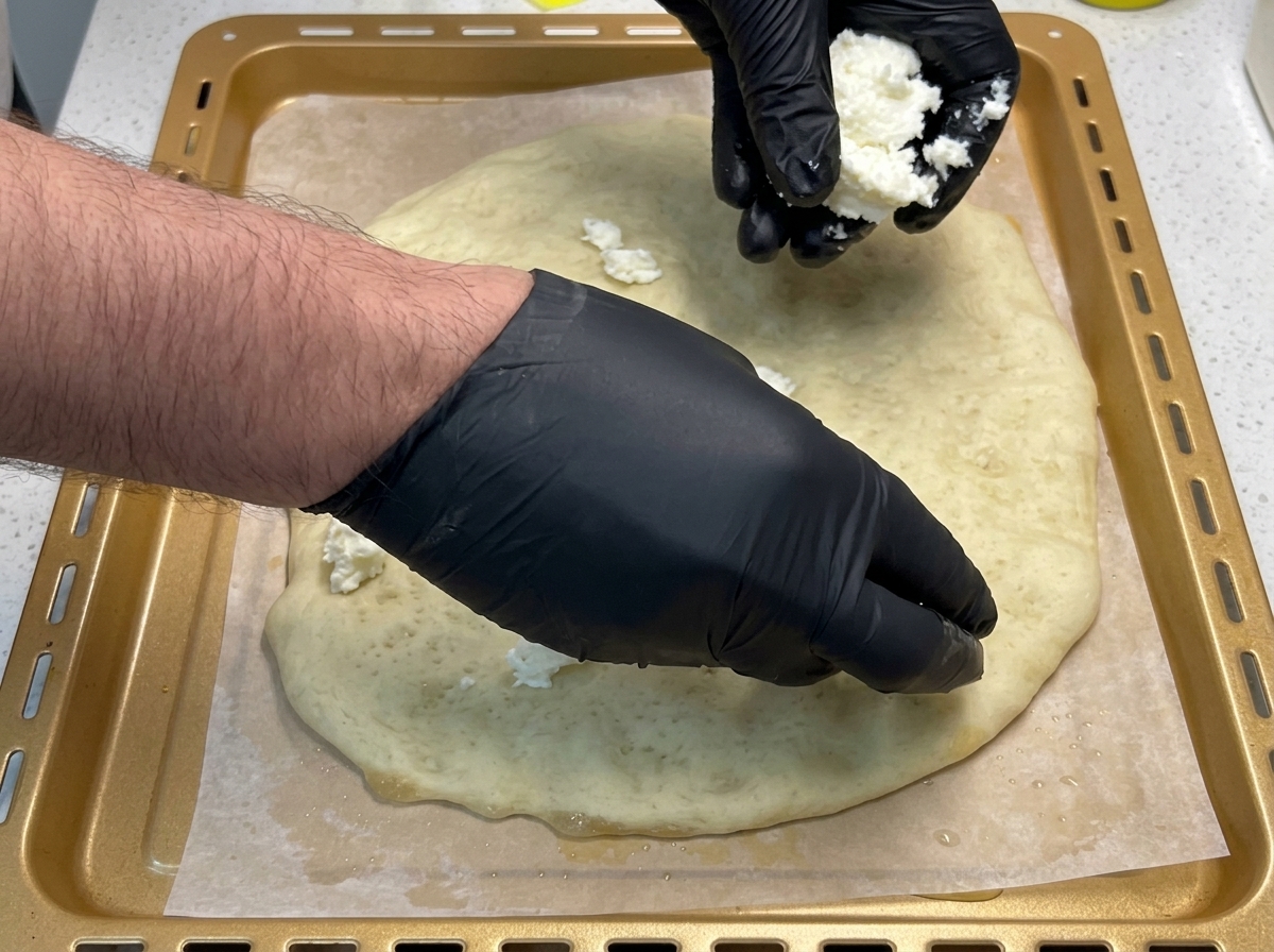 下焼きした生地の上に、手でちぎったモッツァレラチーズを散らしている様子。
