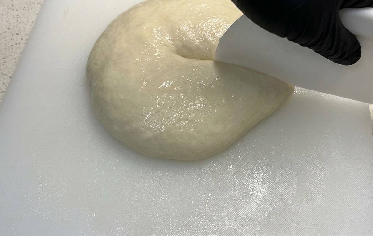 スケッパーを使って、膨らんだ生地を2等分に切り分けている様子。