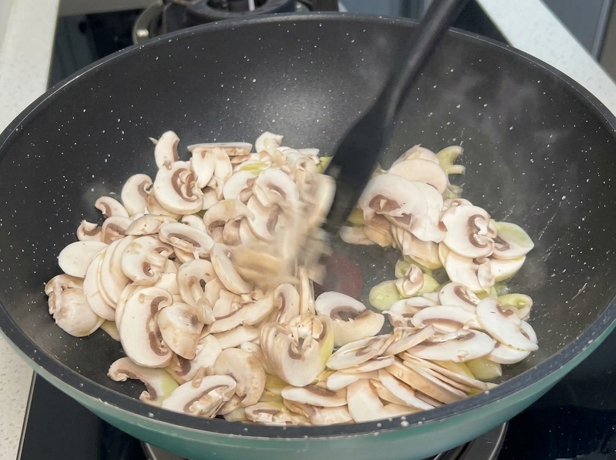 フライパンでキノコとにんにくを炒めている様子。
