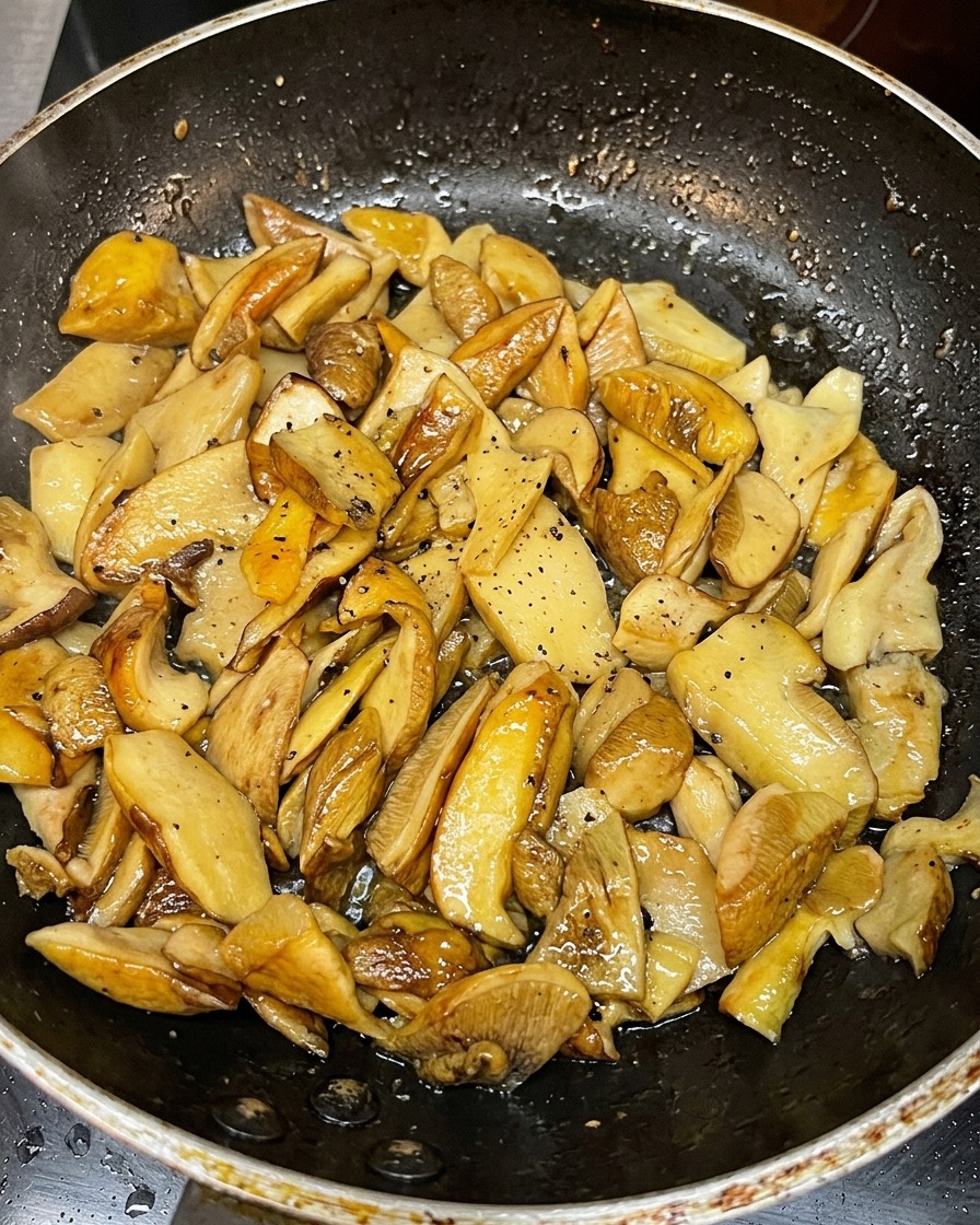 フライパンで黄金色に炒められるスライスしたポルチーニ茸。