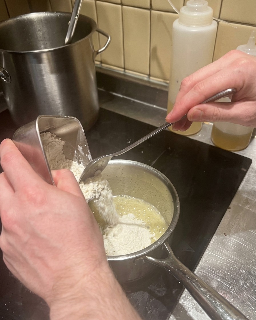 バターとシャロットの混合物に小麦粉を加えてルーを作る様子。