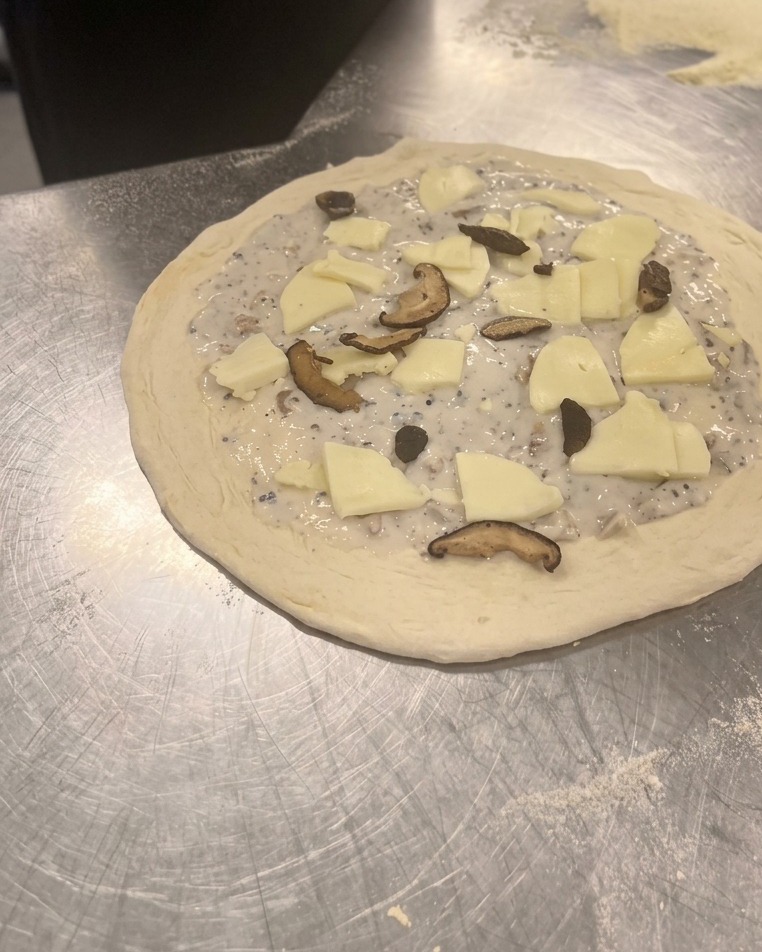 チーズの上に炒めた椎茸とマッシュルームを散らしている様子。