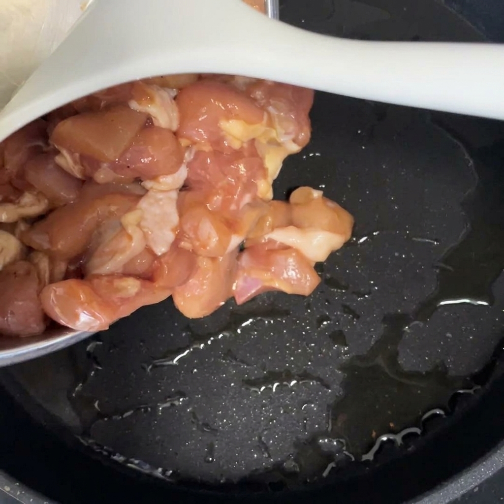 熱したフライパンにマリネした鶏肉を入れている様子
