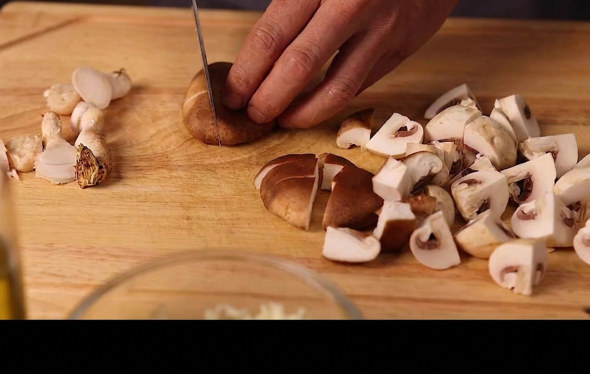 まな板の上で新鮮な椎茸とマッシュルームをスライスする様子。
