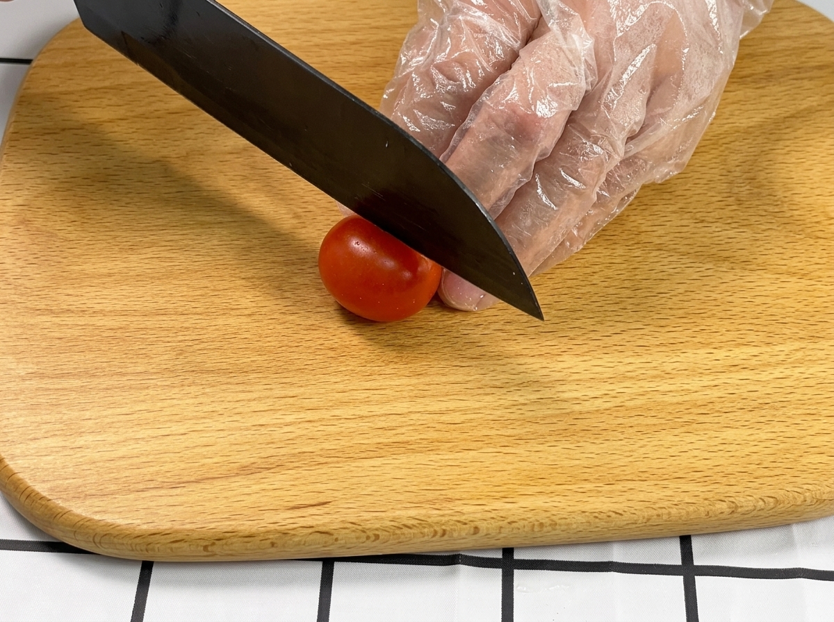 まな板の上でミニトマトを半分にカットしている様子。