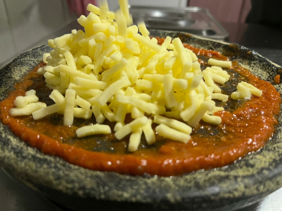 ピザソースの上にたっぷりのシュレッドチーズを散らし、焼き上げる直前の状態。