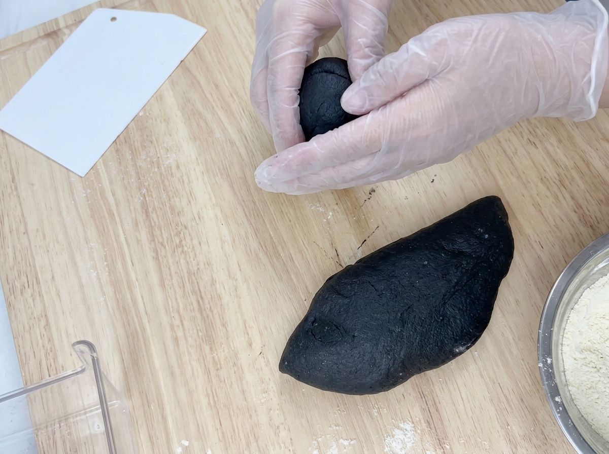 分割した生地を、作業台の上で丁寧に丸め直している様子。