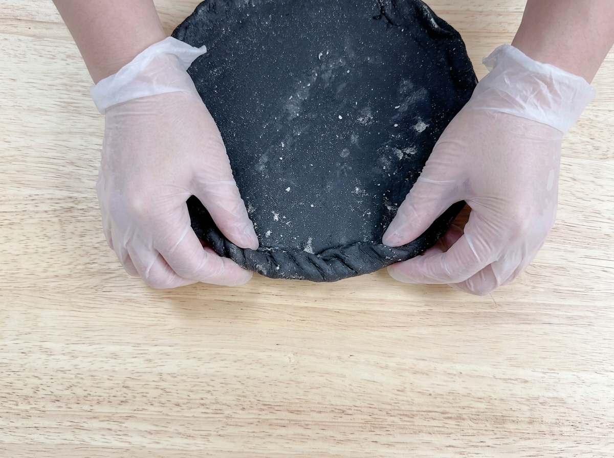 ピザの縁を指でつまみながら、ねじるようにしてしっかり閉じている様子。