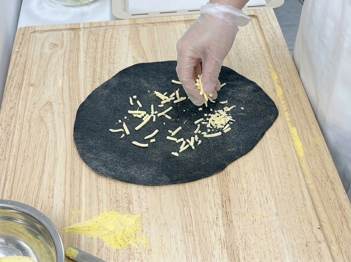 楕円形に伸ばした生地の片側半分だけに、チーズを散らしている様子。