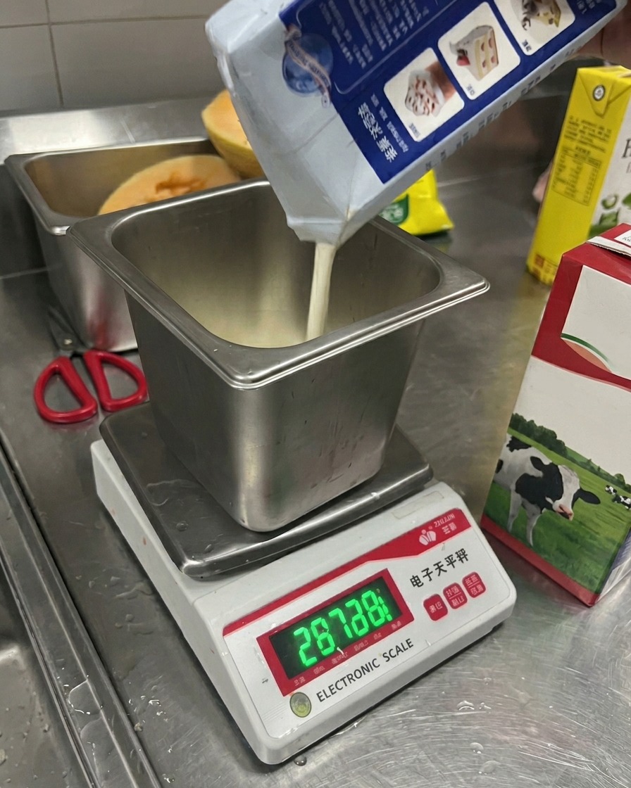 金属製の容器に牛乳と生クリームを注ぎ、デジタルスケールで計っている様子。