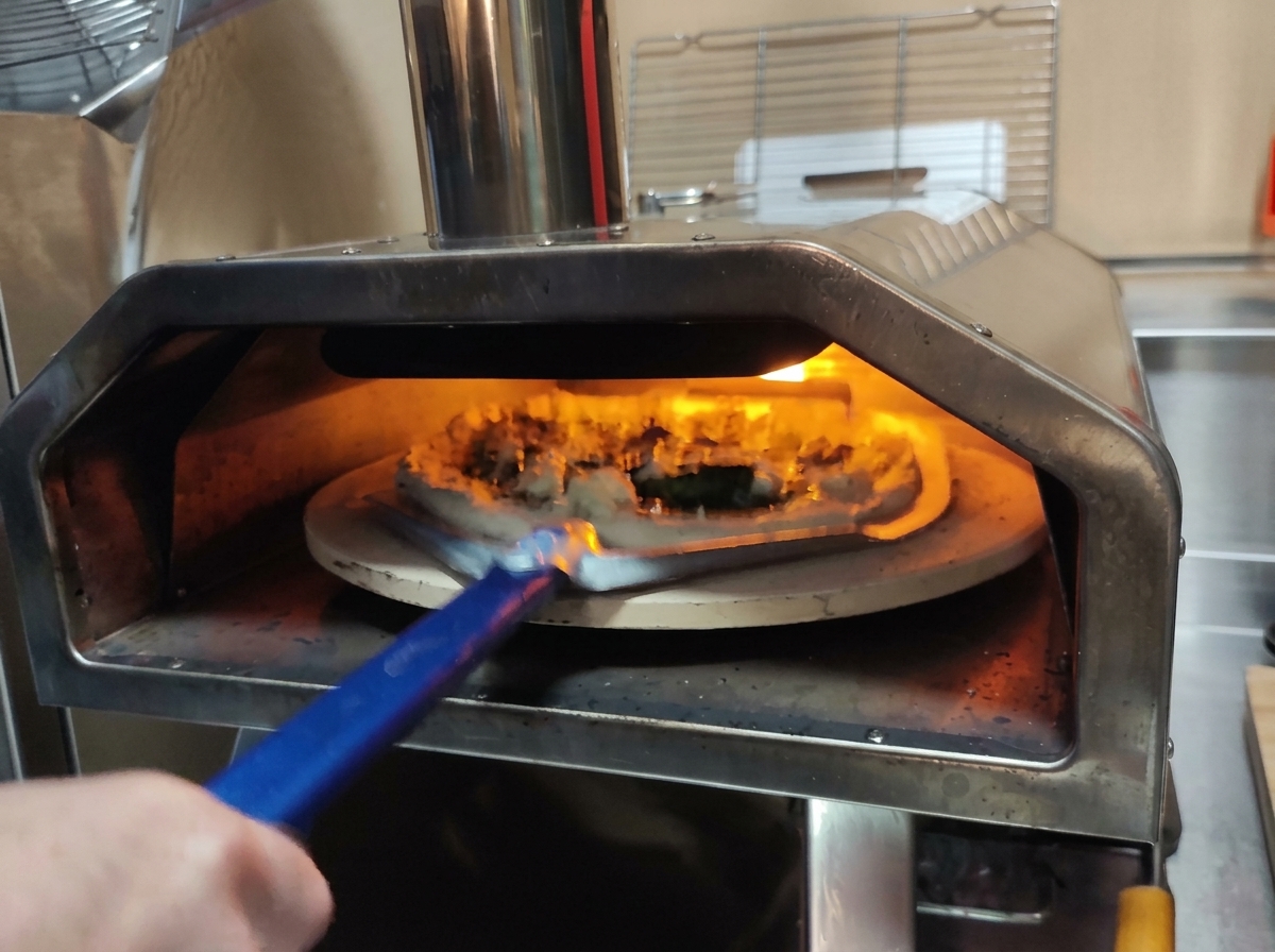 穴あきのピザピールを使って、焼く前のピザを高温のオーブンに入れている様子。