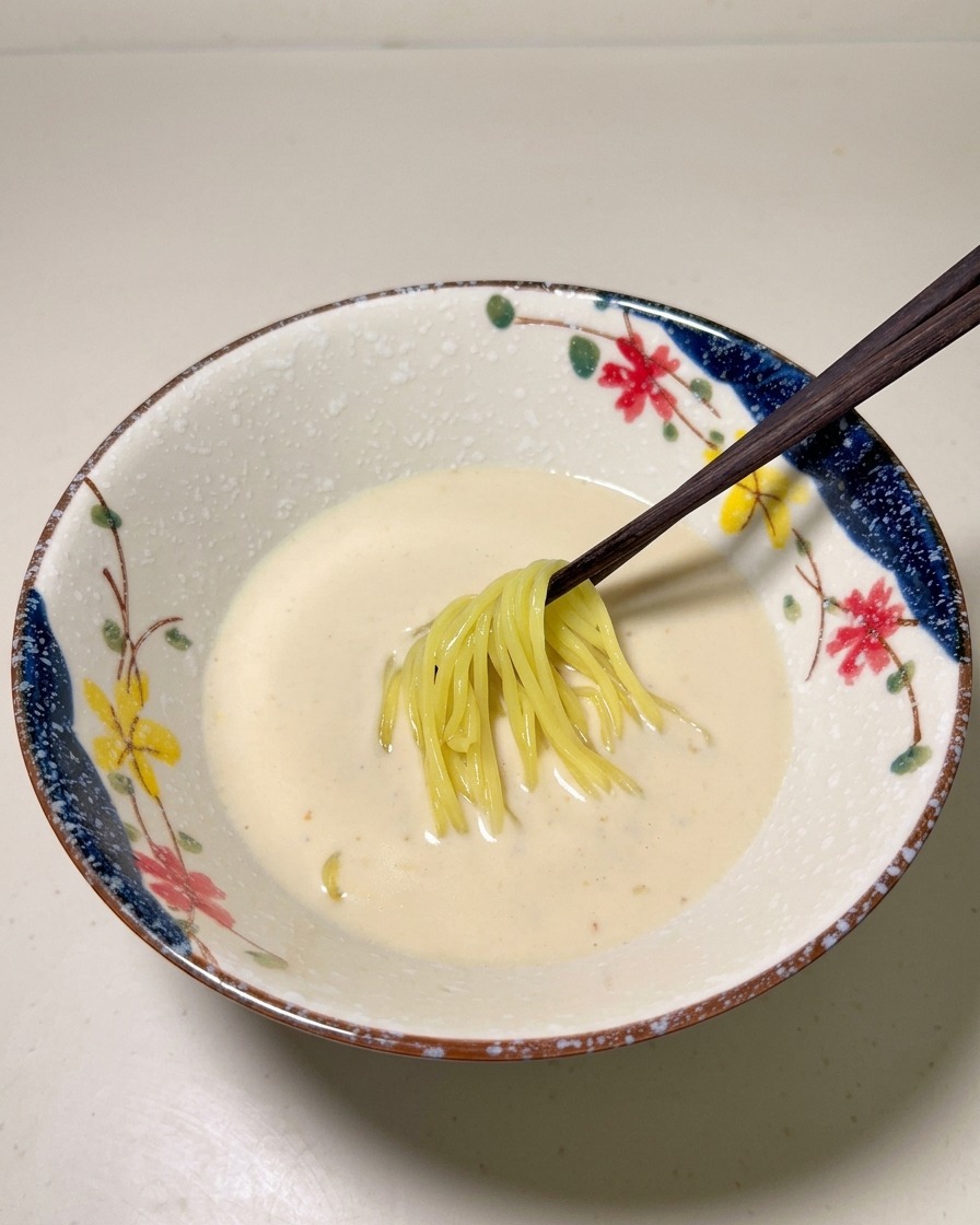 茹で上がった中華麺を、器に張ったスープの中にそっと入れている様子。