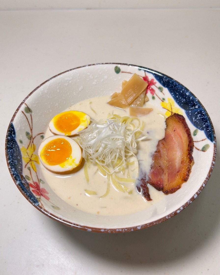 チャーシュー、メンマ、そして白髪ねぎをバランスよく麺の上にのせている様子。