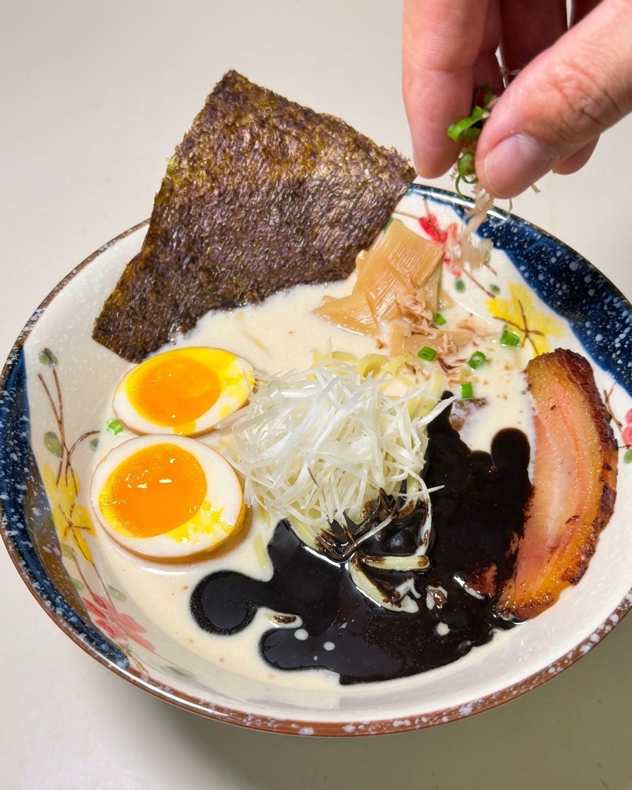 最後に小口切りのねぎを散らし、完成した美しい黒マー油ラーメンの全景。