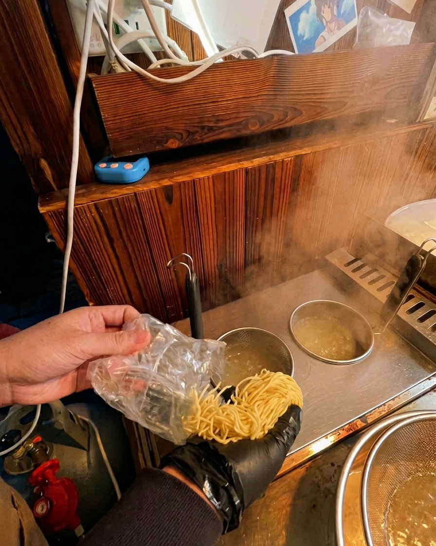 沸騰した鍋に沈めた振りザルの中に、袋から生麺を投入する様子。