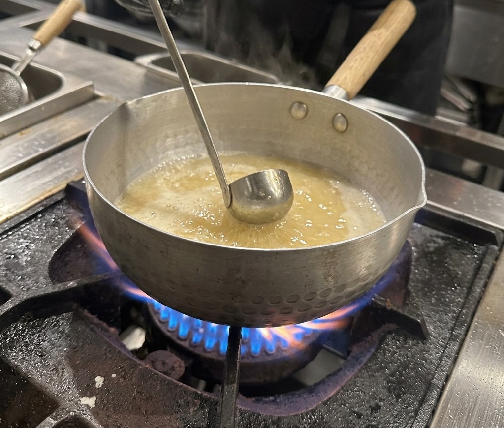 沸騰する鍋の中に、濃口醤油を加えている様子。